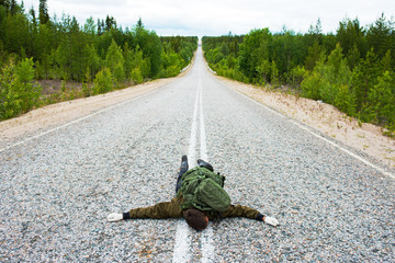 Tourist with a backpack lying on the road
