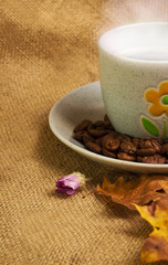 The cup of coffee with maple leaves and everlasting flowers