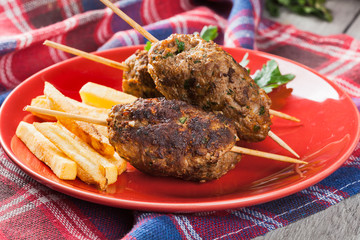 Barbecued kofta with fries on a plate