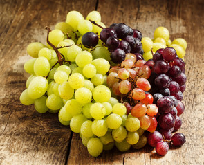 Green, pink and purple grapes on old wooden table, selective foc