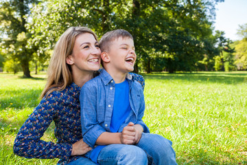 mother tickling her laughing son in the park