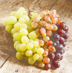 Green, pink and purple grapes on old wooden table, selective foc