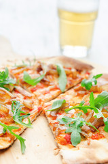 Pizza topped with tomato, caramelised onion and fresh rocket, fresh handmade thin crust and beer