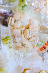 Fototapeta na wymiar Caramel macaroons in a glass bell jar on a white wooden table