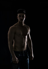 Fototapeta na wymiar Young hip man in jeans, shirtless, isolated on black