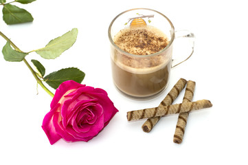 the transparent mug of a cappuccino decorated with a flower and cookies