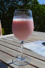 Pink yoghurt drink in a wine glass on a terrace