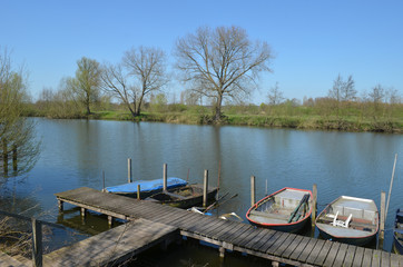Obraz premium Wooden dock with little rowing boats in a river