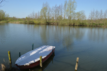 Obraz premium Little rowing boat anchored in a large river