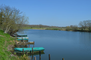 Obraz premium Covered rowing boats docked on a wide river