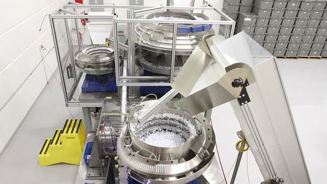 Craning up on a large industrial machine assembling small plastic parts into chapstick product in a clean factory
