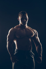 Fototapeta na wymiar Handsome muscular bodybuilder posing over black background.