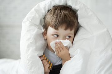 boy wipes his nose with a tissue