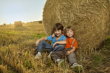 Naklejka na ściany i meble Two boys in a haystack in the field