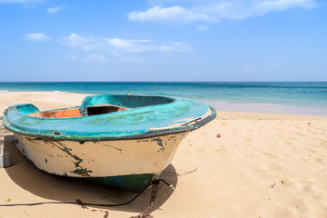 Ruined wooden boat on golden sandy beach in Guadeloupe