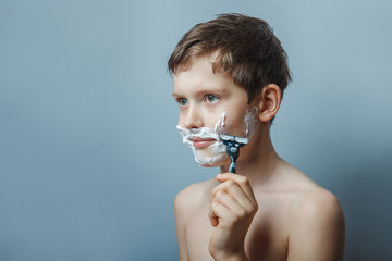 teenage boy 12 years of European appearance with a razor shaves 