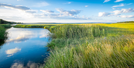 Swedish landscape of marshes and canals with beautiful reflections of clouds and sky. Gotland.
