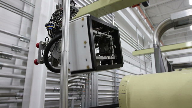 Camera follows the movement of a robotic arm in a factory as it carries a product to the conveyor belt, then picks up a label for the next product
