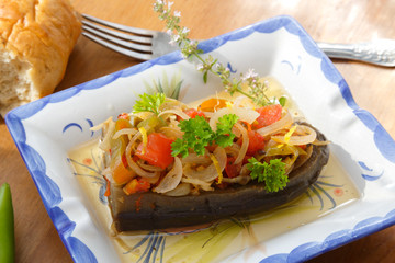 Baked eggplant stuffed with vegetables on wooden background
