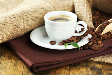 Cup of coffee with beans on table close up