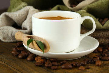 Cup of coffee with beans on table close up