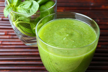 Glass of green healthy juice with spinach and basil on table close up