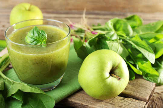 Glass of green healthy juice with spinach and apple on table close up