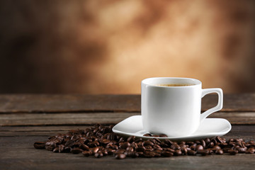 Cup of coffee and beans on blurred background