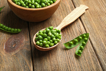Fresh green peas in bowl and spoon on table close up