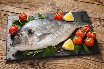 Fresh fish with tomato and lemon on old table