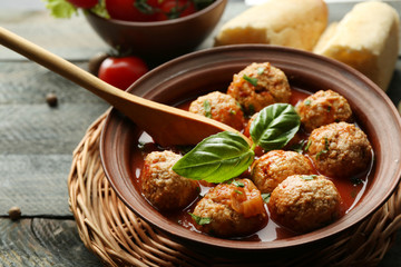 Meat balls with tomato sauce, wooden spoon on wooden background