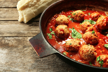 Pan with meat balls in tomato sauce, on wooden background