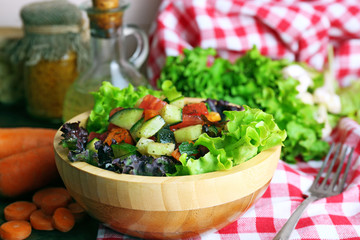 Wooden bowl of fresh vegetable salad on table, closeup