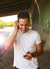 Young man relaxing after jogging.He using his smart phone and listening to music.Typing...