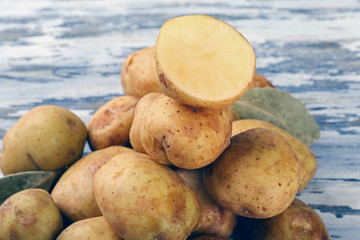 young potatoes with bay leaves on wooden table close up