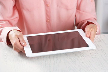 Woman holding digital tablet on table close up