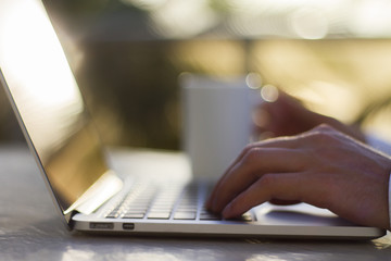 Man working with laptop and cup of coffee at sunrise