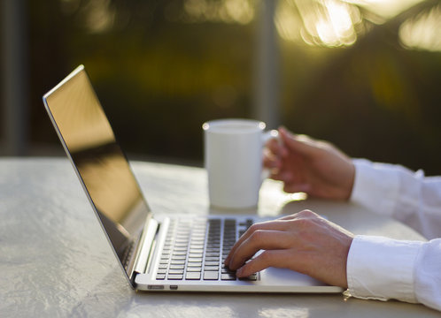 Businessman working with laptop and cup of coffee at sunset