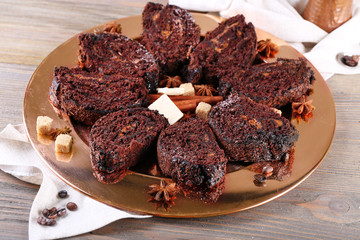 Delicious chocolate roll on metal plate on wooden table, closeup