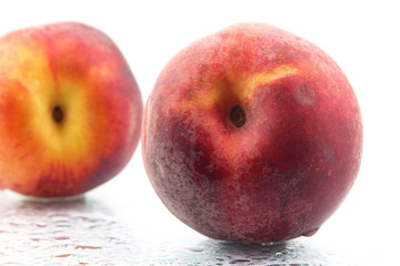 two ripe peaches in the water droplets on white background