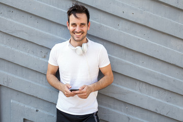 Young man relaxing after jogging.He using his smart phone and listening to music.Typing...