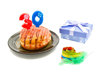 donut with thirty years birthday candle, whistle and gift on whi