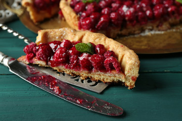Piece of tart with raspberries on tray, close-up, on color wooden background
