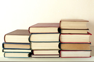 Old books on shelf, close-up, on light wall background