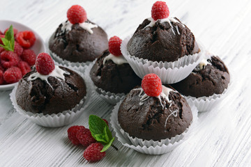Delicious chocolate cupcakes with berries and fresh mint on wooden table close up