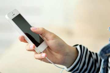 Music smartphone in female hand, on light background