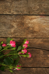 Fototapeta na wymiar Beautiful small roses on wooden background