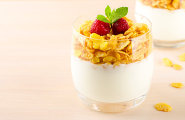 Breakfast with cereal flakes, yogurt and fresh raspberries