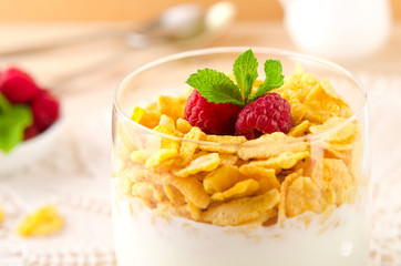 Breakfast with cereal flakes, yogurt and fresh raspberries