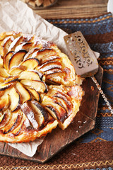 Homemade apple pie on cutting board on wooden background
